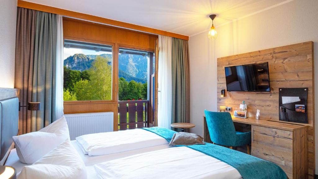 インツェルにあるDas Wiesgauer - Alpenhotel Inzellのベッド2台と窓が備わるホテルルームです。