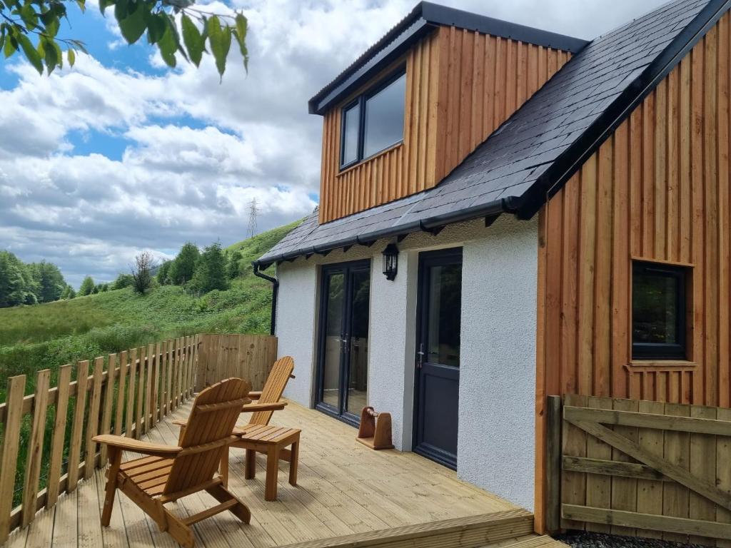 a wooden deck with two chairs and a house at Cozy Nook in Spean Bridge