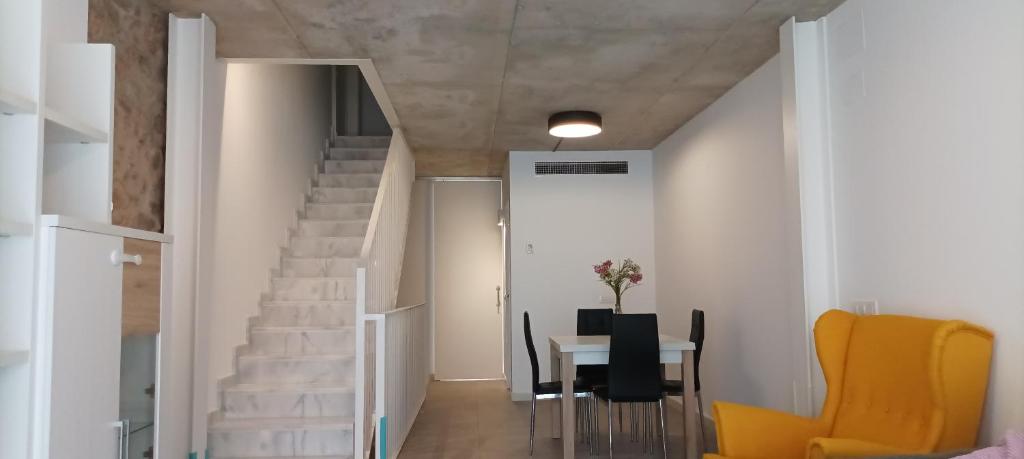 Una escalera en una habitación con una mesa y sillas amarillas. en Casa Bayer, en Benicàssim