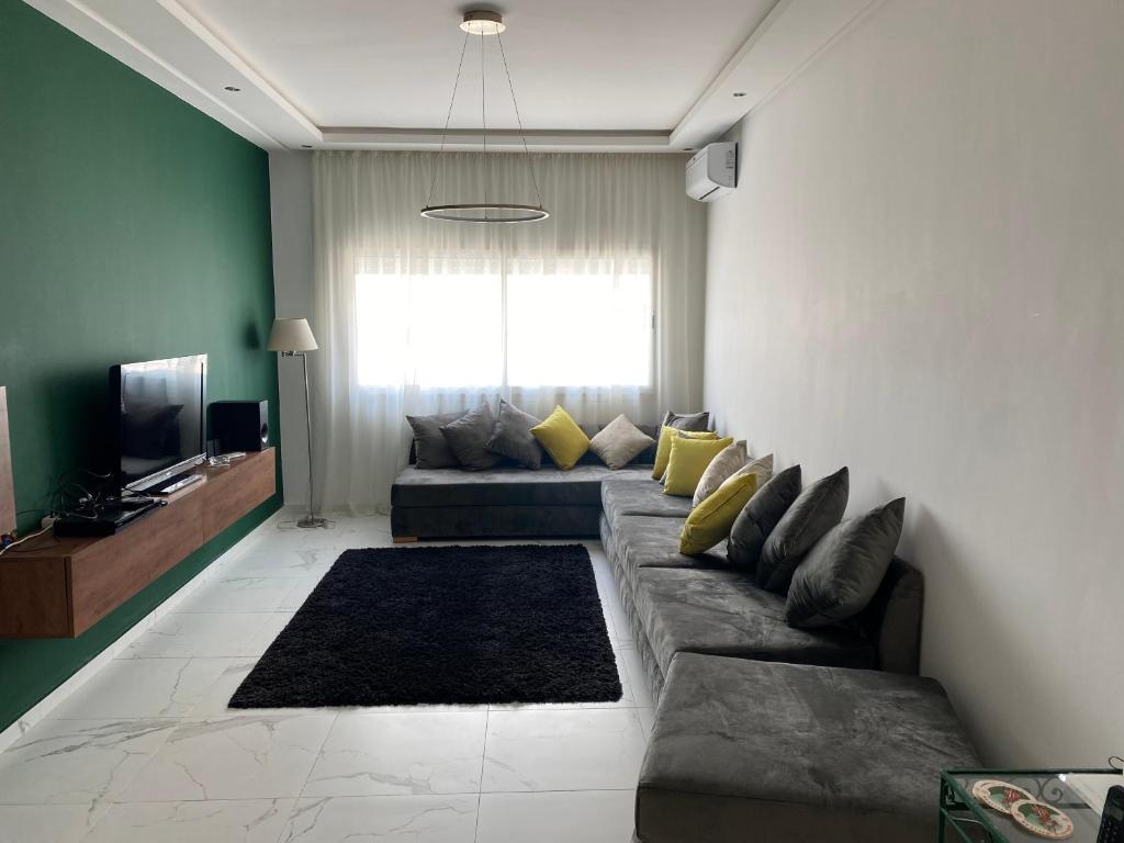 a living room with a couch and a television at Lovely 4-bedroom condo with pool in Rabat