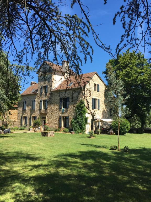 a large stone house in a field of grass at Chambres et table d'hôtes Le cèdre Aveyron in Sainte-Croix