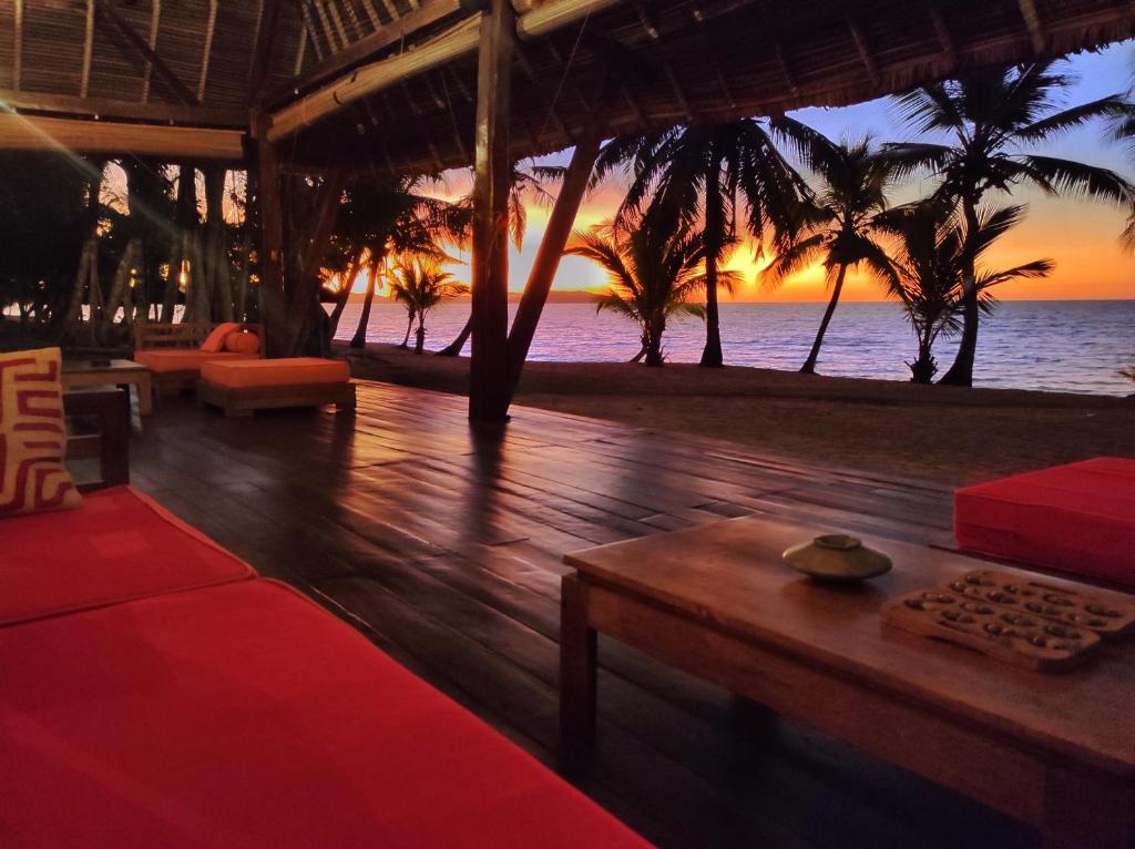 a living room with a view of the ocean at sunset at Eden Lodge in Nosy Be