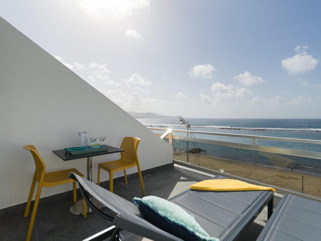 einen Balkon mit einem Tisch und Stühlen sowie Meerblick in der Unterkunft Luxury Suite Over The Beach in Las Palmas de Gran Canaria