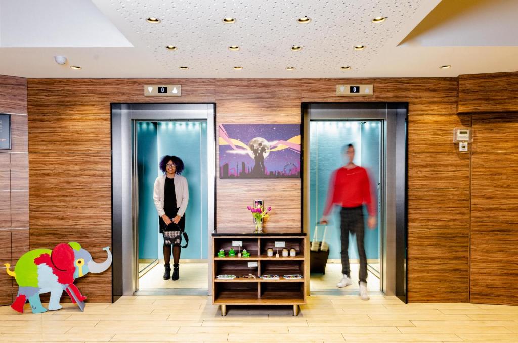 Kobieta chodząca między dwoma szklanymi drzwiami w centrum handlowym w obiekcie Ibis Styles Wien City w Wiedniu