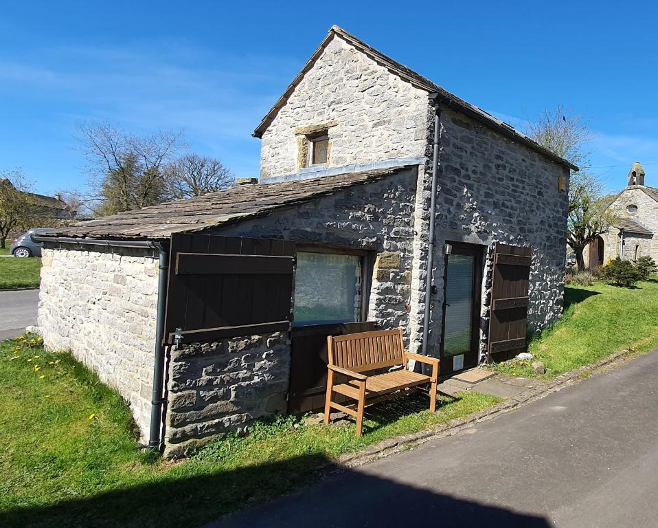an old stone building with a bench in front of it at Sandy's Barn, Foolow, Dogs Welcome in Foolow