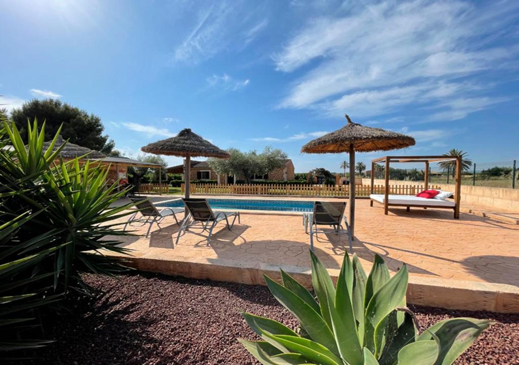 una piscina con 2 sombrillas y 2 sillas y un columpio en Son Sea Villa, en Campos