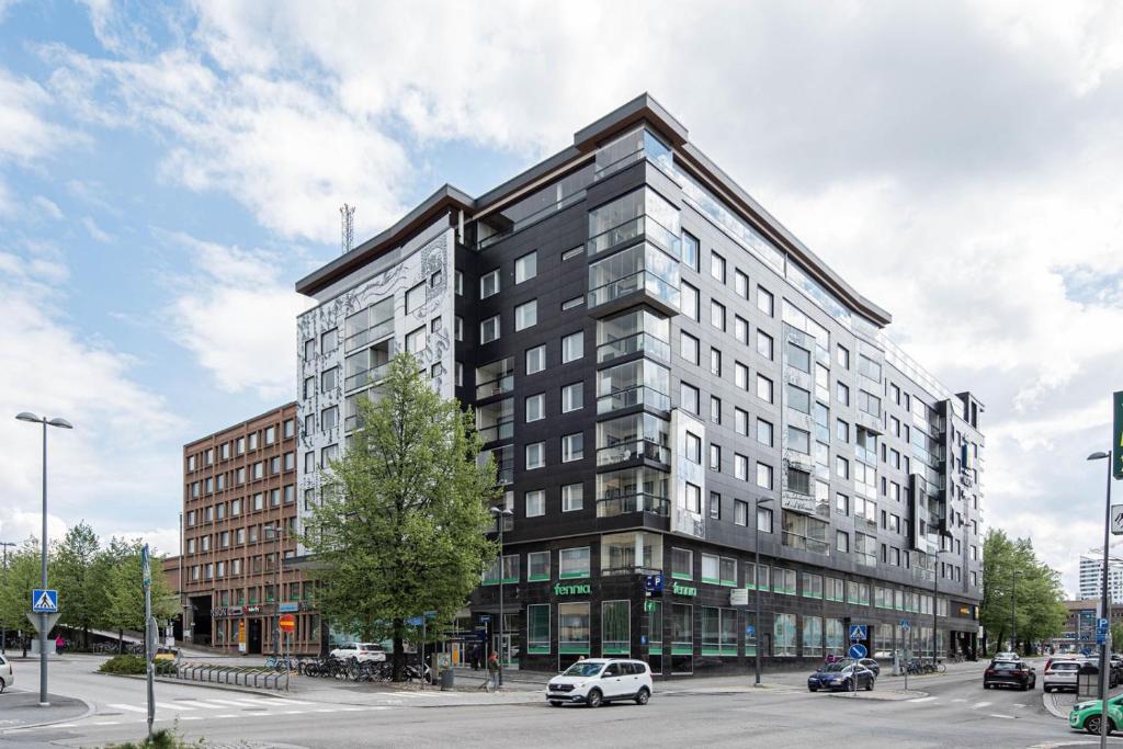ein hohes Gebäude in einer Stadtstraße mit einem Auto in der Unterkunft 2ndhomes Tampere "Posteljooni" Apt - New 1BR Apt with Balcony and Best Location in Tampere