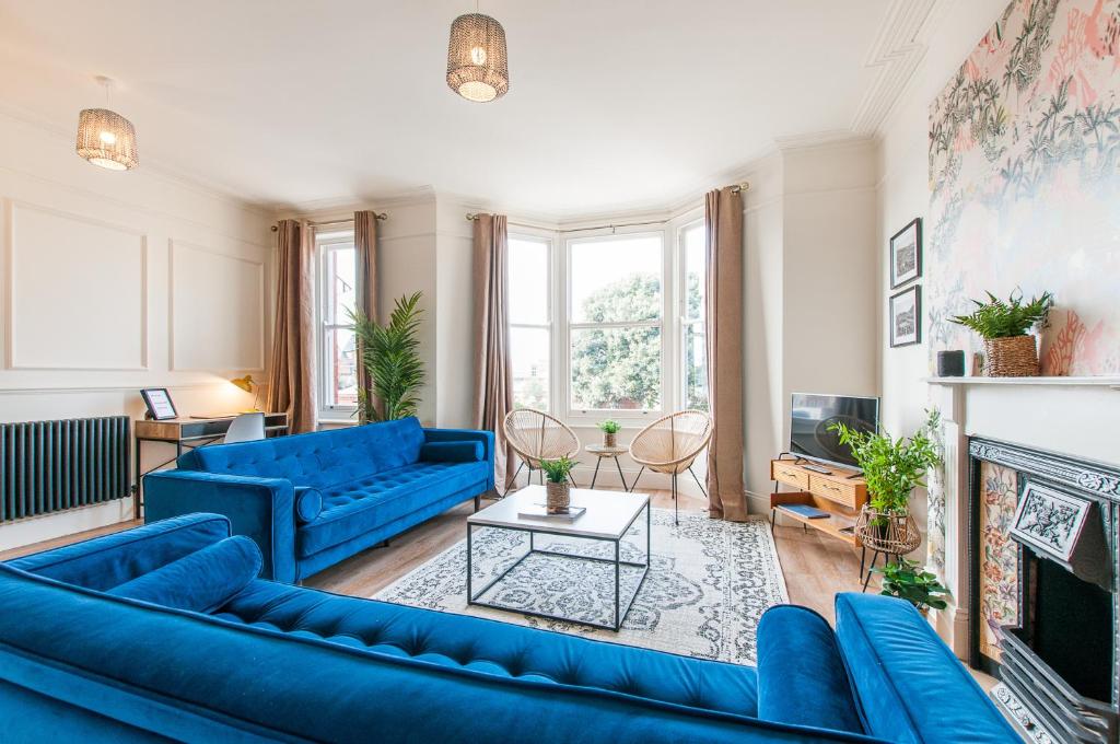 a living room with blue couches and a fireplace at Queen Palm Apartment - Margate - 3 mins walk to beach in Margate