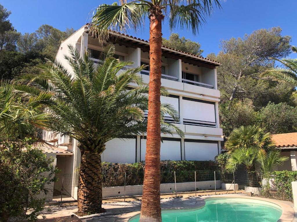 a building with palm trees in front of a swimming pool at Hôtel de la plage in Agay - Saint Raphael