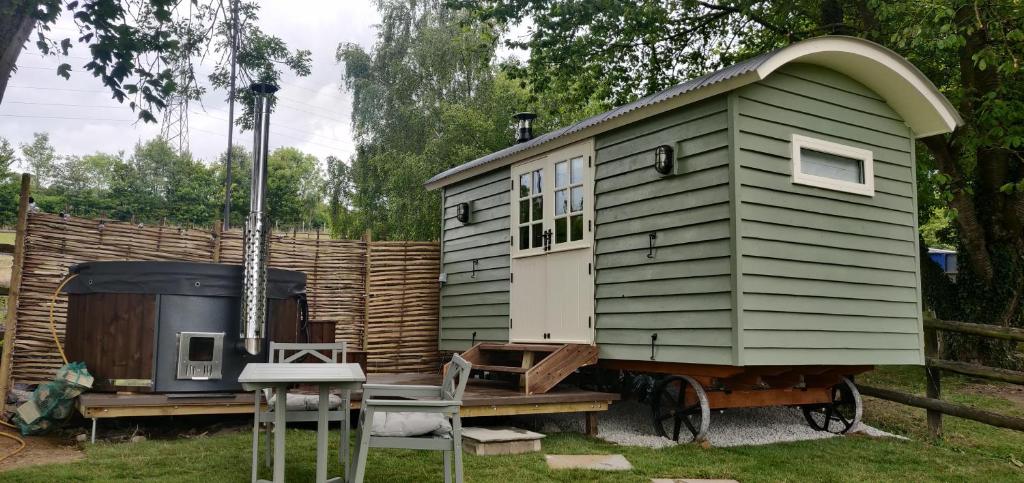 a green tiny house sitting on top of a truck at Romantic Shepherds hut with stunning sunsets in Hollingbourne