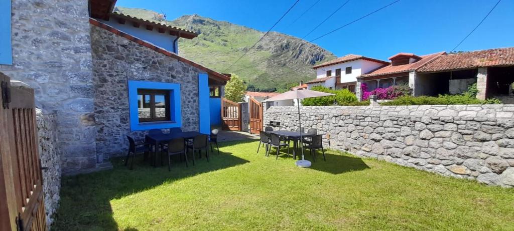 a house with a stone wall and a table and chairs at Vivienda Vacacional El Refugio in Llanes