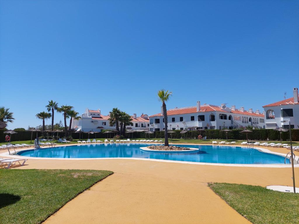 une grande piscine avec des palmiers et des bâtiments dans l'établissement A Mar, à El Rompido