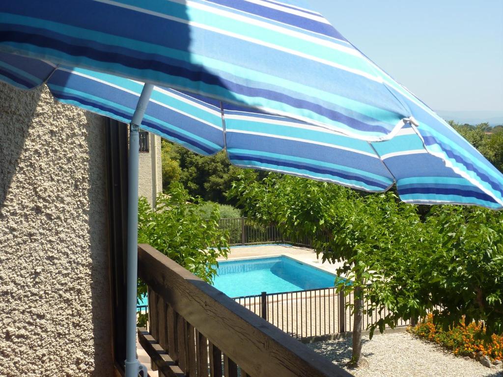 een blauwe en witte parasol naast een zwembad bij Grand Studio Avec Piscine Presqu'île De Giens in Hyères