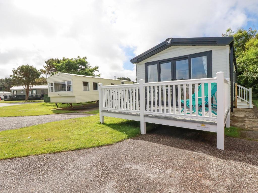 a tiny house with a white railing and a porch at 205 The Meadows in Newquay