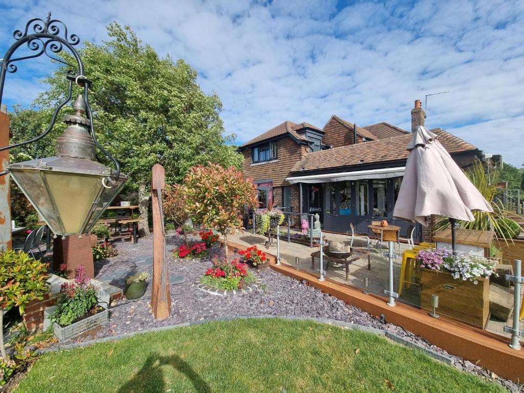 a garden with an umbrella and a house at Varr House @ Meadow View in Woodmancote