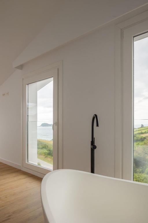 a white room with a tub and two windows at Hotel Boutique Berazadi Berri in Zarautz