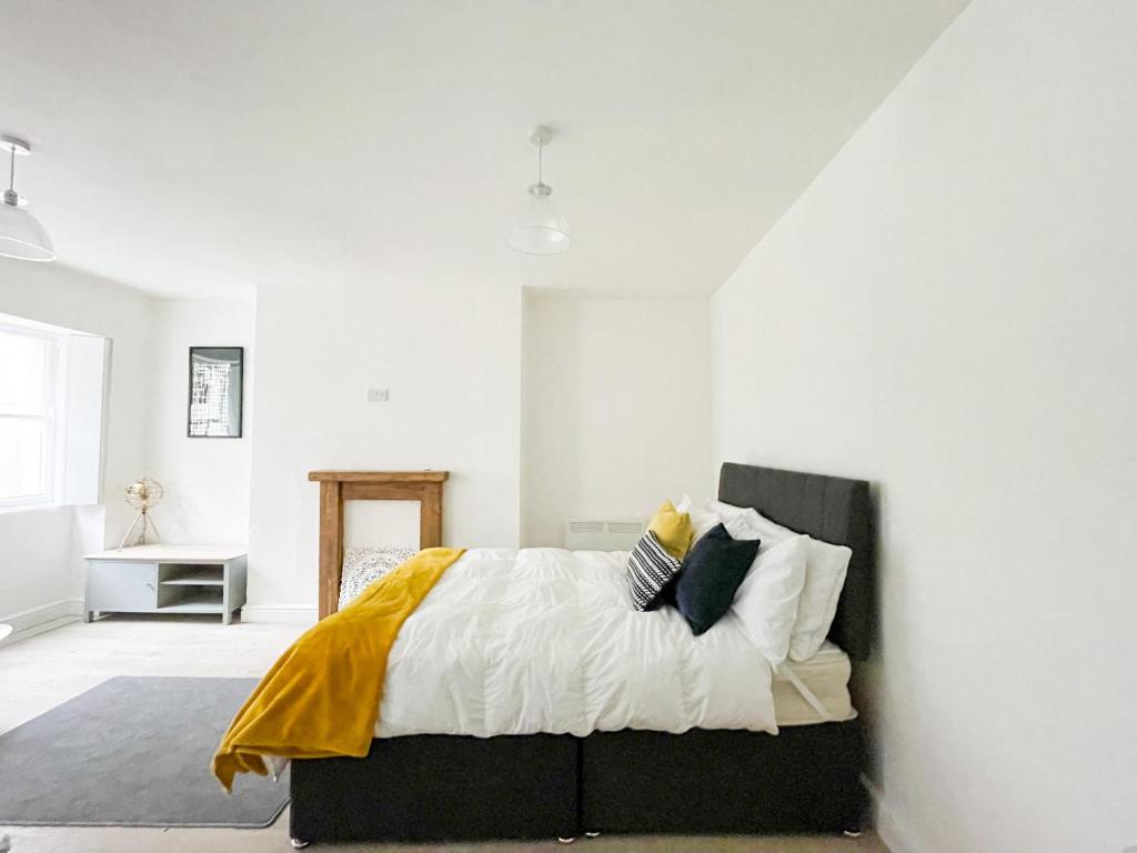 a white bedroom with a bed with a yellow blanket at Pittville Studios - By Suitely in Cheltenham