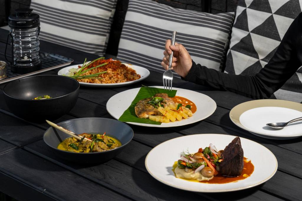 A shared table presents several plated Thai dishes and bowls.