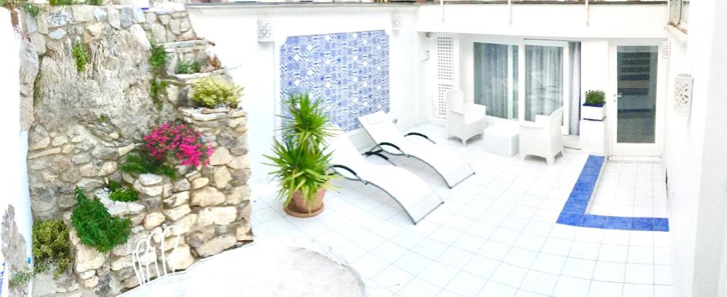 a patio with white furniture and a stone wall at Marilù vacation home in Positano in Positano