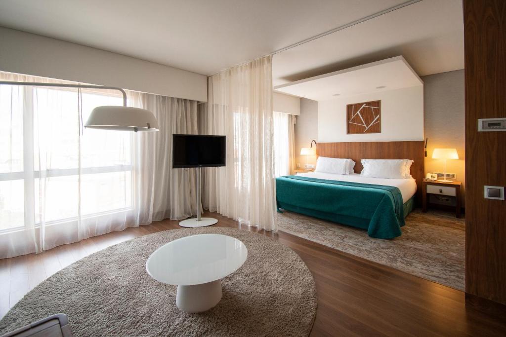 An open-plan suite-style room with a separate sitting area, television and king bed.