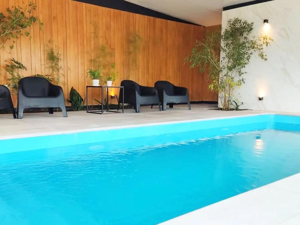 uma piscina com cadeiras e uma mesa ao lado em La Bonita Suites Punta Colorada em Punta Colorada
