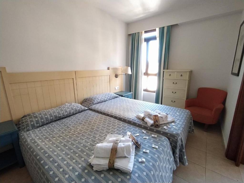 sypialnia z 2 łóżkami, ręcznikami i krzesłem w obiekcie APARTAMENTO VISTAS LATERALES AL MAR SEGUNDA PLANTA w mieście Isla Canela