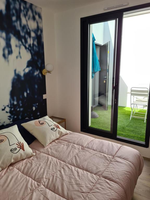 uma cama num quarto com uma grande janela em Location LA REBELLE - LA ROCHELLE B em La Rochelle