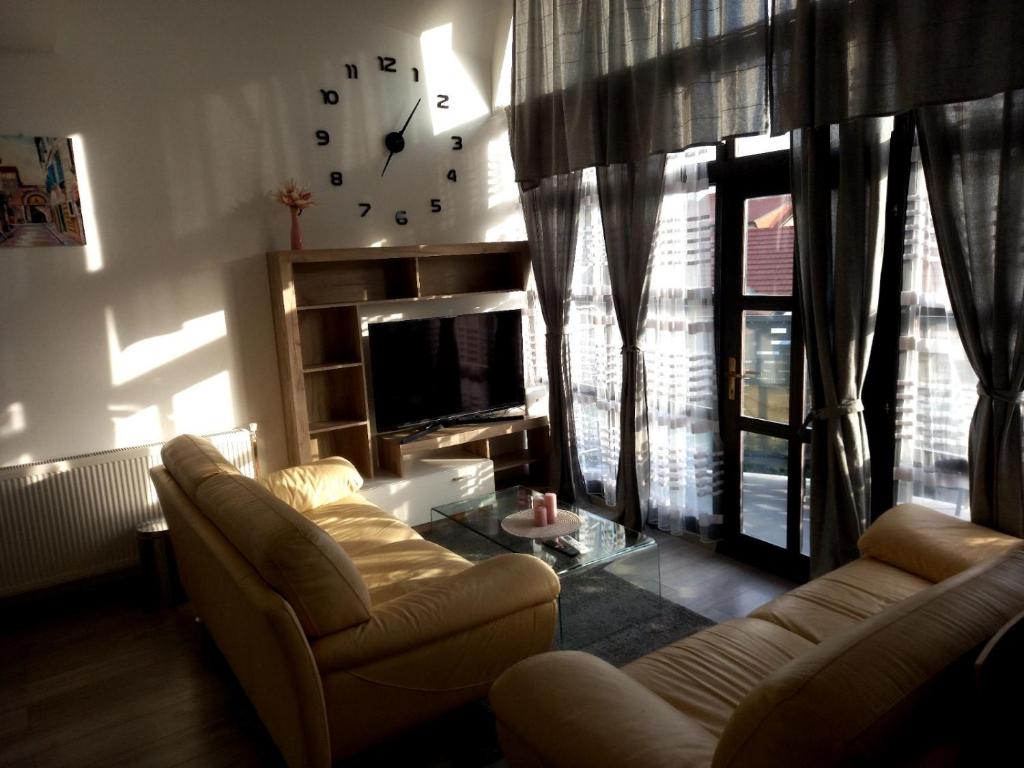 salon z kanapą i zegarem na ścianie w obiekcie Apartmani Dubrava 1 w Zagrzebiu