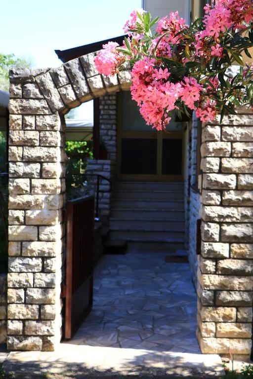 Un arco de piedra con flores rosas. en Family rooms Moela, en Umag