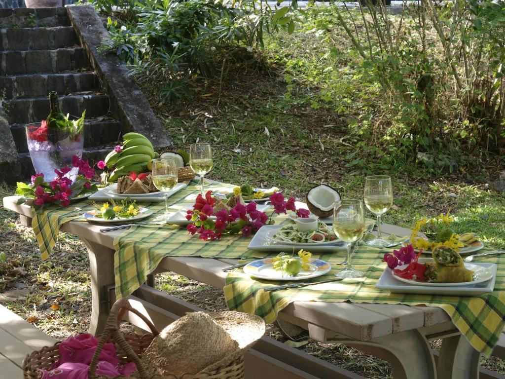 a picnic table with plates of food and wine glasses at Firefly Estate Bequia in Crescent Beach