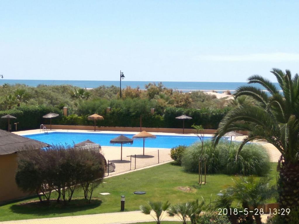 vista para uma piscina a partir de um resort em PRECIOSO APARTAMENTO JUNTO AL MAR em Isla Canela