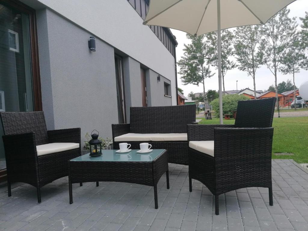 um pátio com cadeiras, uma mesa e um guarda-sol em M&M Apartamenty Wicie em Wicie