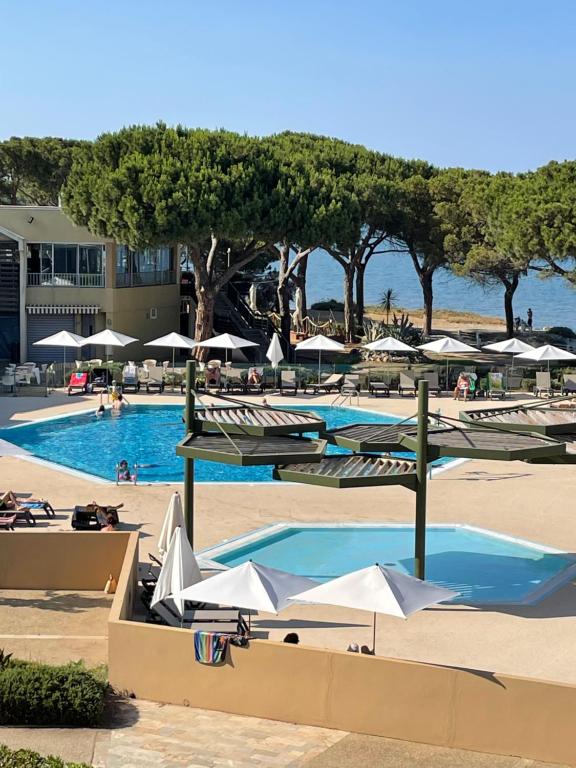 a pool with umbrellas and chairs and a beach at Le Village des Isles in Taglio-Isolaccio