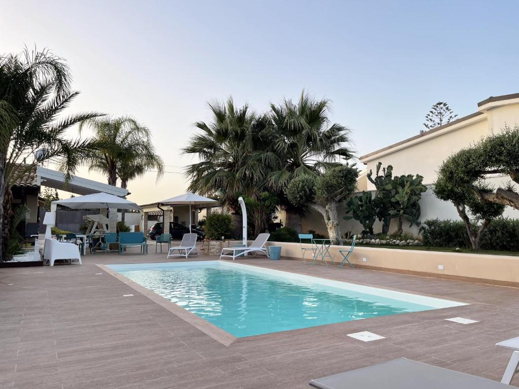 a swimming pool in a resort with palm trees at Xenìa - Villa con Piscina Privata in Agrigento