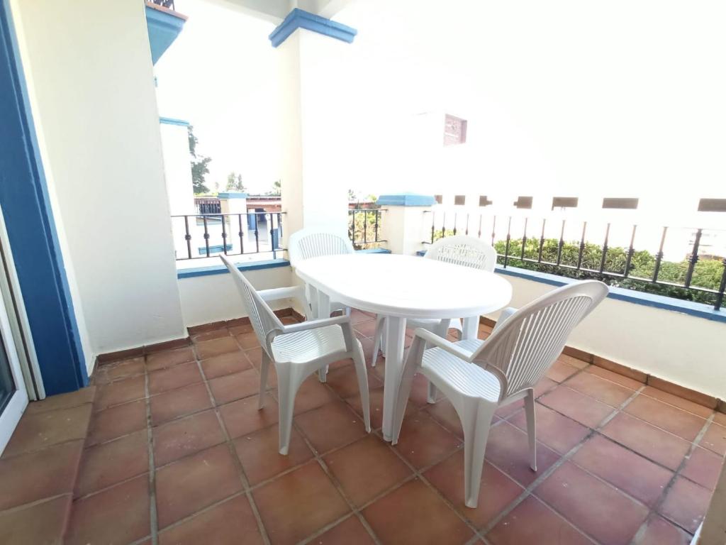 d'une table et de chaises blanches sur un balcon. dans l'établissement Acogedor apartamento a 50 metros de la playa, à Isla Canela