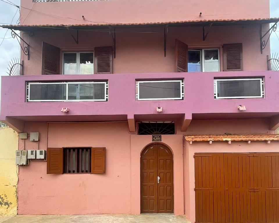 een roze huis met deuren en ramen bij Chez Titi in Saint-Louis