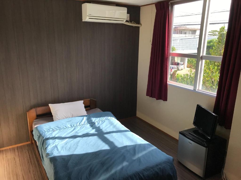 niewielka sypialnia z łóżkiem i oknem w obiekcie Minshuku Green-so - Vacation STAY 92548v w mieście Uechi