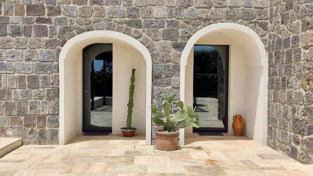 two arched entrances to a stone building with a potted plant at Nostos - Casale e Permacultura in SantʼAgata sui Due Golfi
