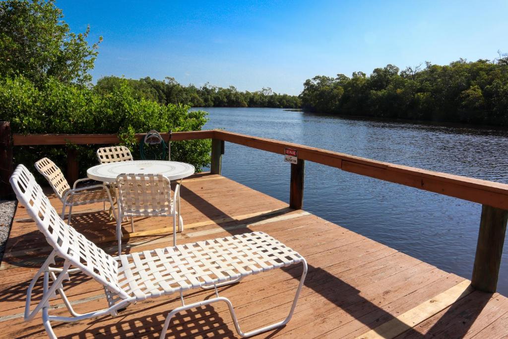 una mesa y sillas en una terraza de madera junto al agua en River Wilderness Waterfront Cabins, en Everglades