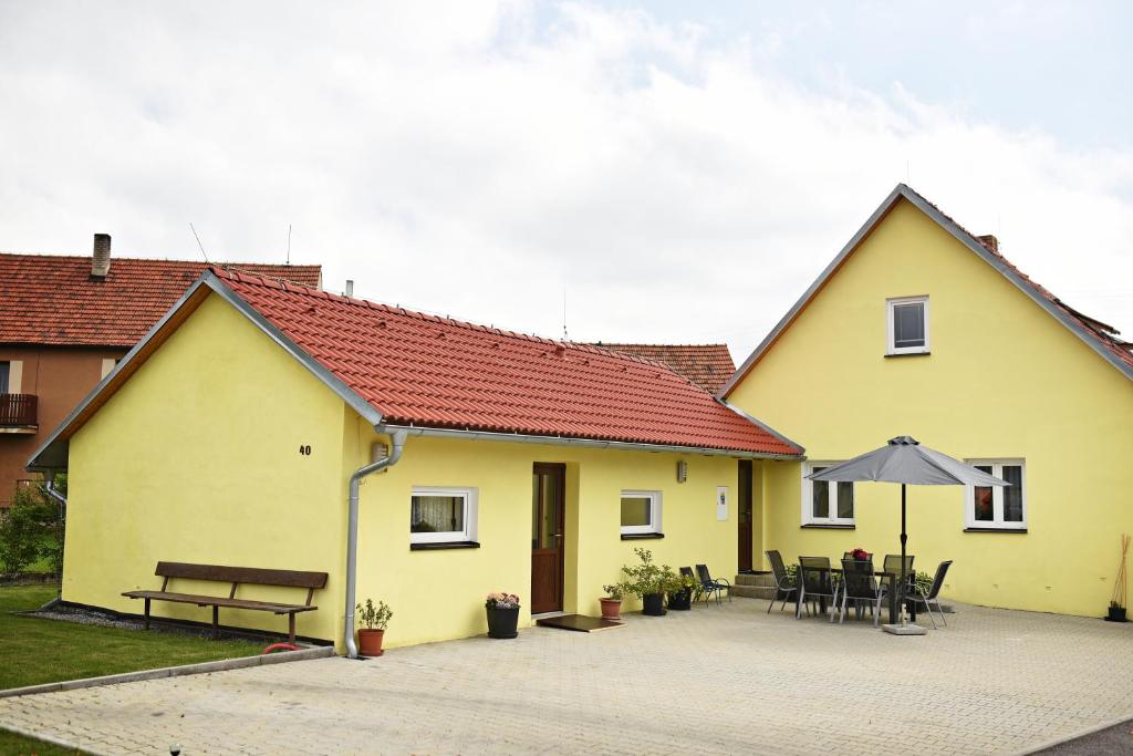 Casa amarilla con mesa y sombrilla en Penzion Rozárka en Přísečná