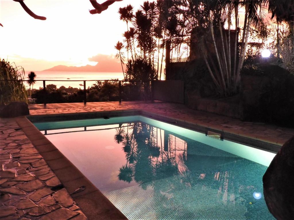 uma piscina com um pôr-do-sol ao fundo em TAHITI - Studio Te Maraamu em Faaa