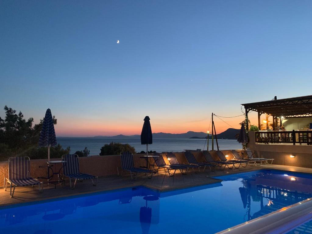 a villa with a swimming pool at dusk at Panorama Apartments in Marathokampos