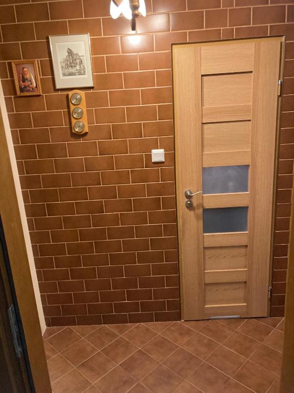 a bathroom with a brick wall and a door at Apartament Roma in Gdańsk