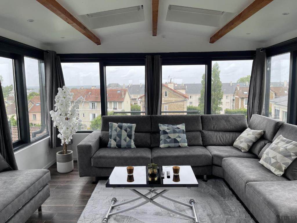 een woonkamer met een bank en een tafel bij Appartement T2, très cosy, vue panoramique in Saint-Cyr-lʼÉcole