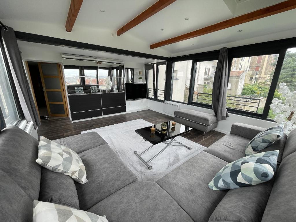 a living room with a couch and some windows at Appartement T2, très cosy, vue panoramique in Saint-Cyr-lʼÉcole