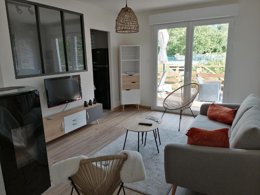 een woonkamer met een bank en een tv bij Le Petit Cabanon in Sapois