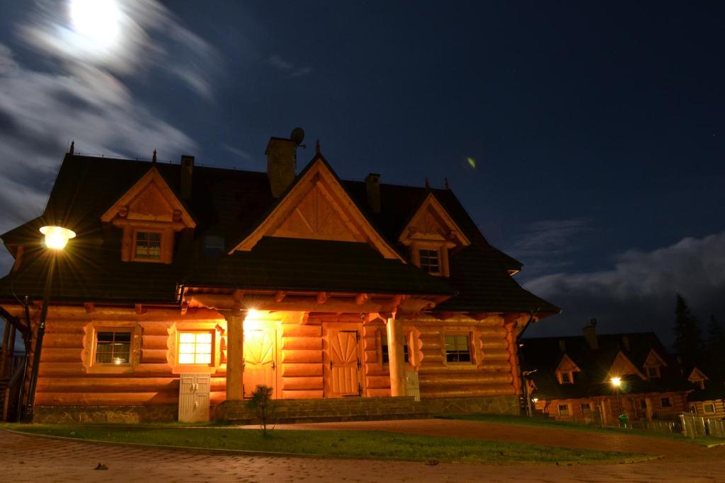 una cabaña de madera por la noche con la luna en el fondo en Apartament Rysulówka 180, en Kościelisko