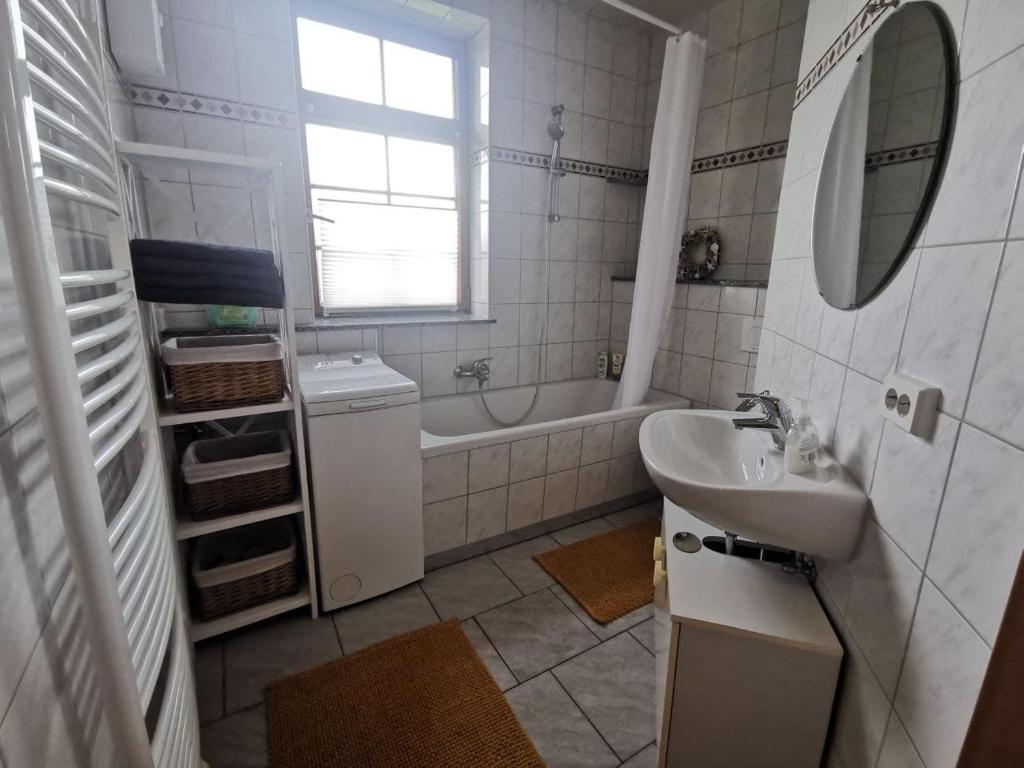 un bagno bianco con lavandino e vasca di Ruhige Ferienwohnung im Gutshaus a Niederorschel