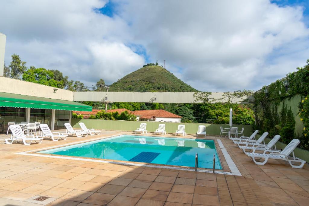 a swimming pool with lounge chairs and a hill in the background at VOA Hotel União in Caxambu