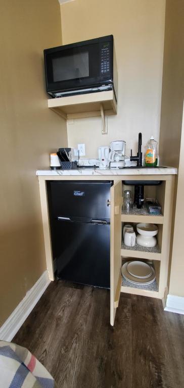 a kitchen with a microwave and a black dishwasher at Fair Isle Motel & The Nest in Whycocomagh